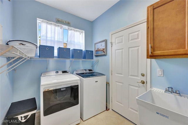 laundry area featuring washer and clothes dryer, light tile patterned flooring, sink, and cabinets