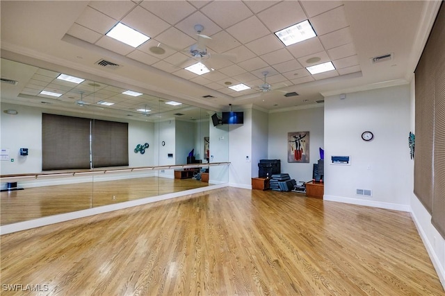 workout area featuring ceiling fan, a paneled ceiling, ornamental molding, and light wood-type flooring