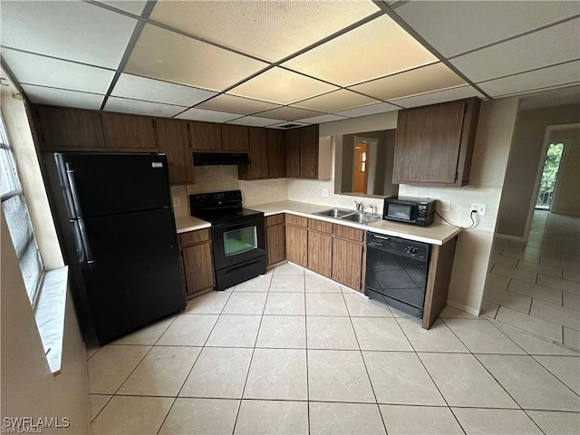 kitchen featuring a paneled ceiling, exhaust hood, black appliances, sink, and light tile patterned floors