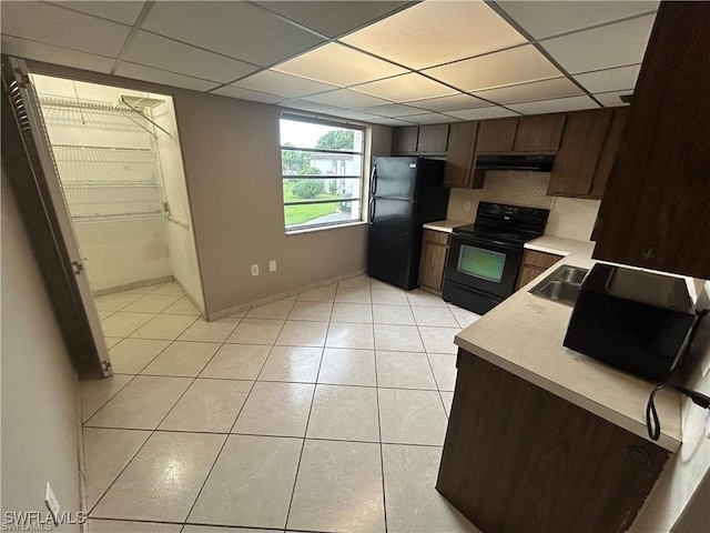 kitchen with tasteful backsplash, range hood, a paneled ceiling, dark brown cabinets, and black appliances