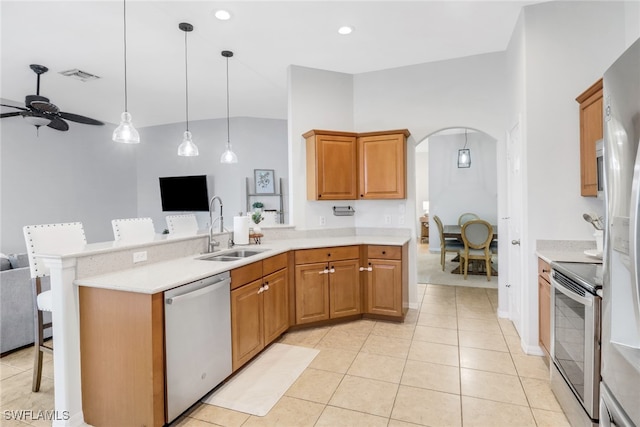 kitchen featuring stove, stainless steel dishwasher, a breakfast bar, ceiling fan, and sink