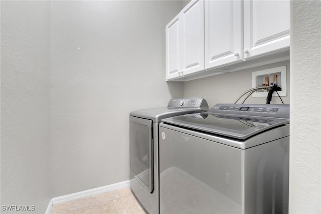 clothes washing area featuring separate washer and dryer, light tile patterned floors, and cabinets