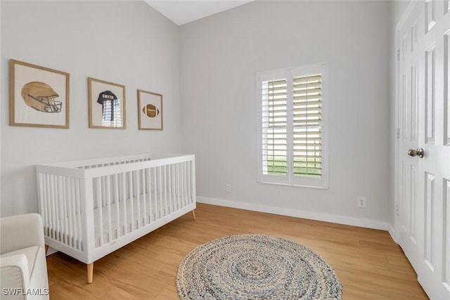 bedroom with multiple windows, wood-type flooring, and a crib