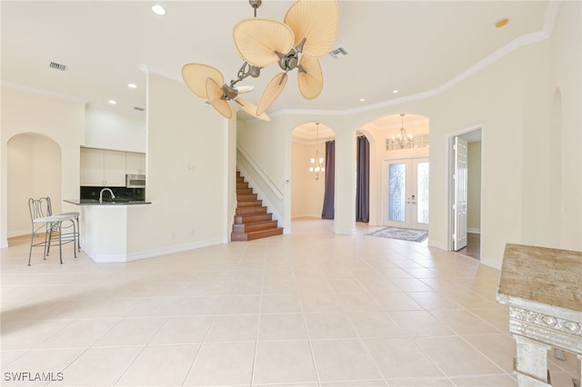 unfurnished living room with crown molding, french doors, light tile patterned flooring, and ceiling fan with notable chandelier