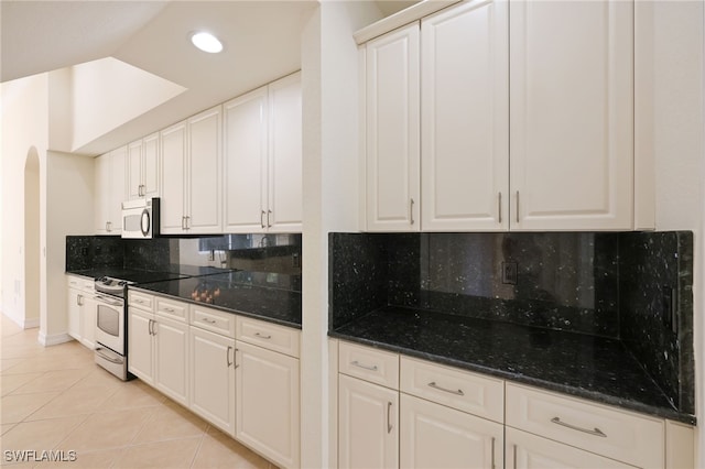 kitchen featuring light tile patterned floors, white cabinets, tasteful backsplash, and white appliances