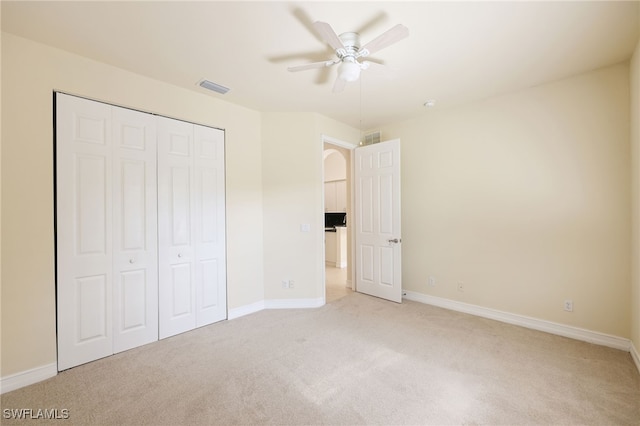 unfurnished bedroom featuring ceiling fan, light colored carpet, and a closet