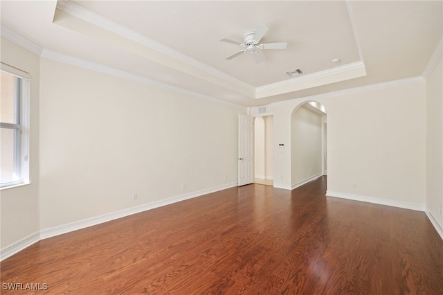 empty room featuring ceiling fan, dark wood-type flooring, a tray ceiling, and ornamental molding