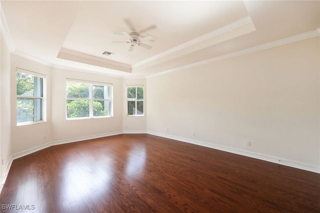 spare room with dark wood-type flooring, ornamental molding, a tray ceiling, and ceiling fan