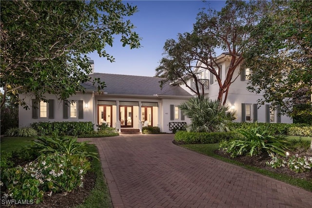 view of front of house with decorative driveway, a tile roof, and stucco siding