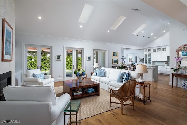 living room featuring a skylight, wood finished floors, french doors, a fireplace, and recessed lighting