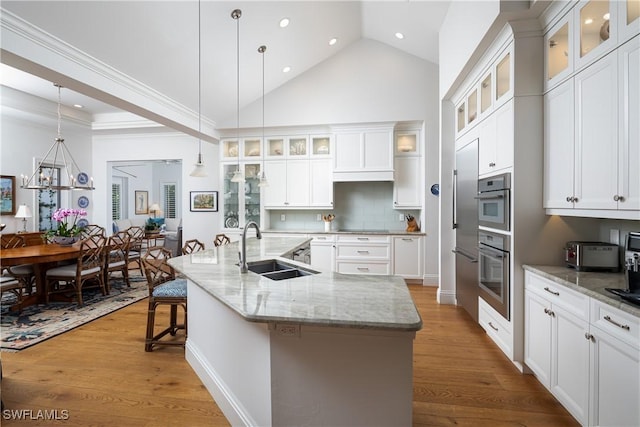 kitchen featuring a large island, a sink, glass insert cabinets, and decorative light fixtures