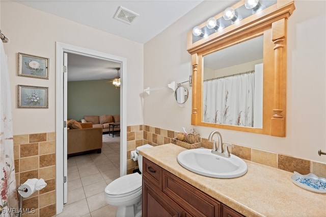 bathroom with tile walls, vanity, ceiling fan, toilet, and tile patterned floors