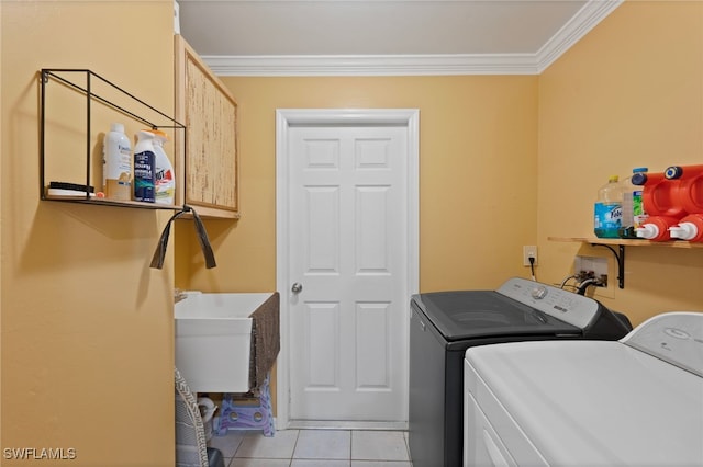 washroom with sink, light tile patterned floors, crown molding, cabinets, and independent washer and dryer