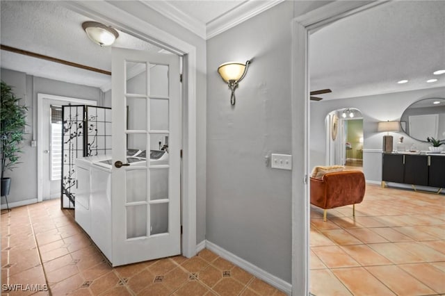 tiled foyer with washing machine and dryer, ceiling fan, a textured ceiling, and ornamental molding