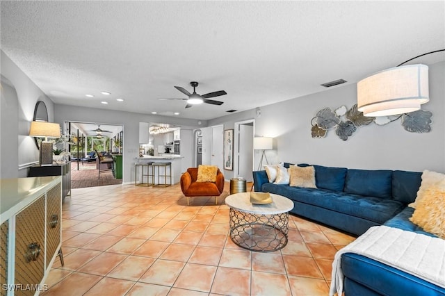 tiled living room with ceiling fan and a textured ceiling