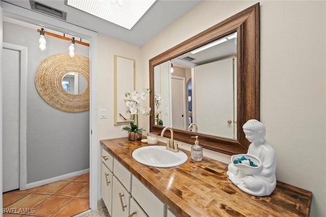 bathroom with tile patterned flooring, vanity, and a skylight