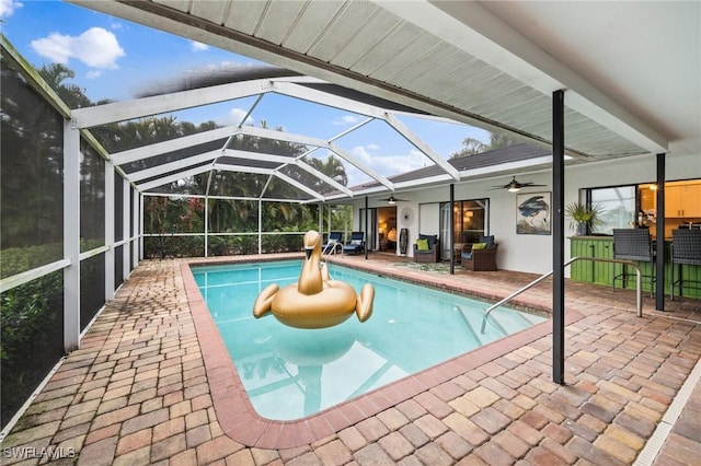 view of swimming pool with a lanai, a patio area, ceiling fan, and exterior bar