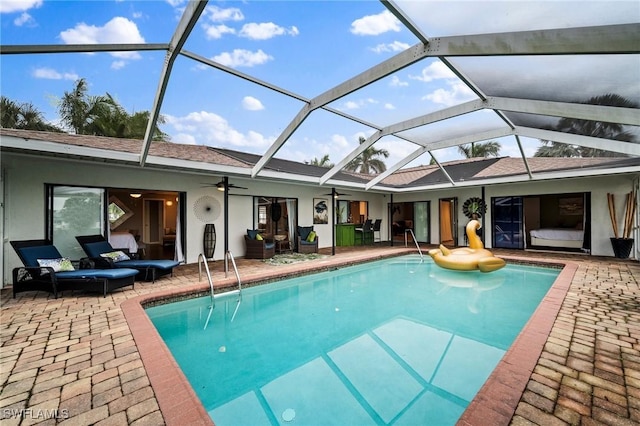 view of swimming pool with glass enclosure, ceiling fan, and a patio area