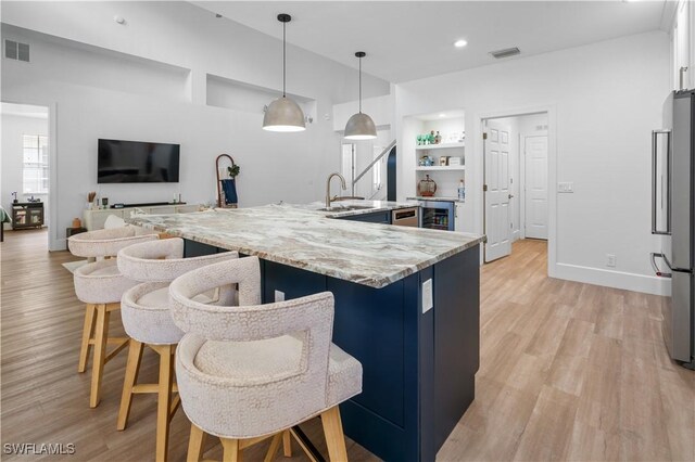 kitchen featuring built in shelves, light stone countertops, stainless steel fridge, pendant lighting, and white cabinets