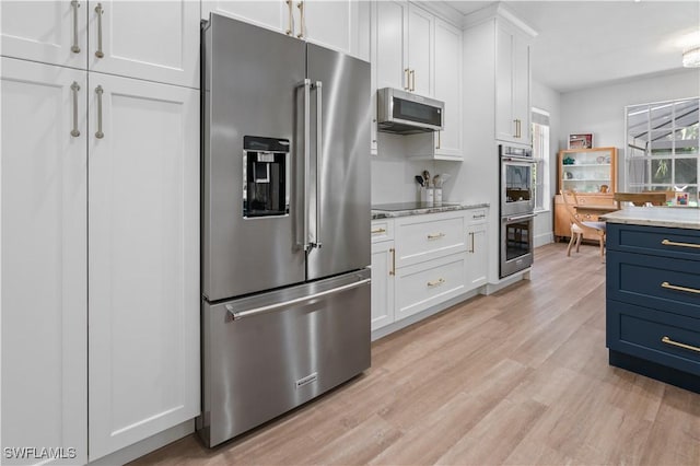 kitchen featuring white cabinets, blue cabinets, light hardwood / wood-style flooring, light stone countertops, and appliances with stainless steel finishes