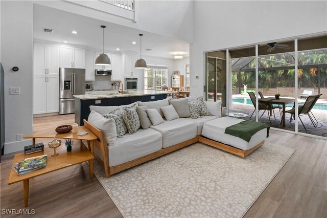 living room with a high ceiling, light hardwood / wood-style floors, and sink