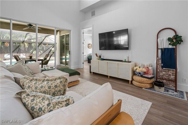 living room featuring a high ceiling, dark hardwood / wood-style flooring, and ceiling fan