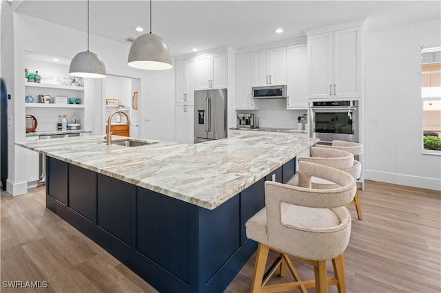 kitchen featuring pendant lighting, white cabinets, a spacious island, sink, and stainless steel appliances