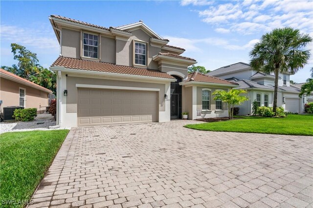 mediterranean / spanish-style home featuring a garage, central air condition unit, and a front lawn