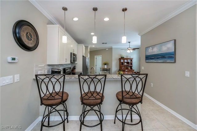 kitchen featuring a kitchen breakfast bar, kitchen peninsula, stainless steel appliances, and white cabinetry