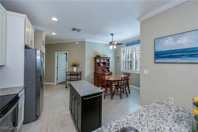 kitchen featuring ceiling fan, light tile patterned floors, crown molding, white cabinets, and stainless steel fridge