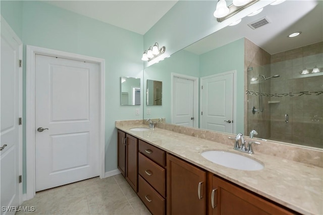 bathroom with tile patterned flooring, a shower with shower door, and vanity