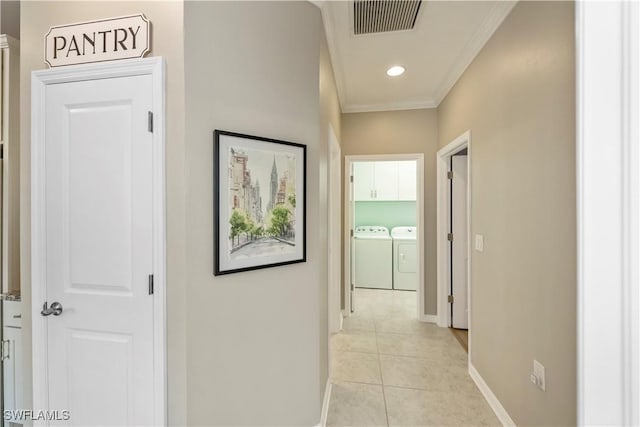 hallway featuring light tile patterned flooring, independent washer and dryer, and ornamental molding