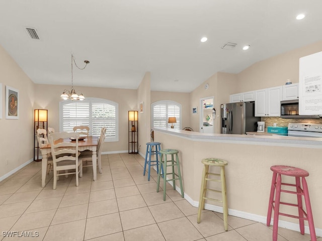 kitchen featuring stainless steel appliances, decorative light fixtures, a chandelier, white cabinetry, and lofted ceiling