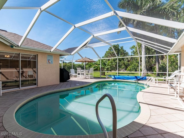 view of pool with glass enclosure and a patio