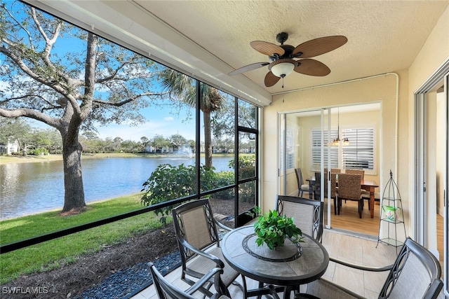 sunroom featuring a water view and ceiling fan with notable chandelier