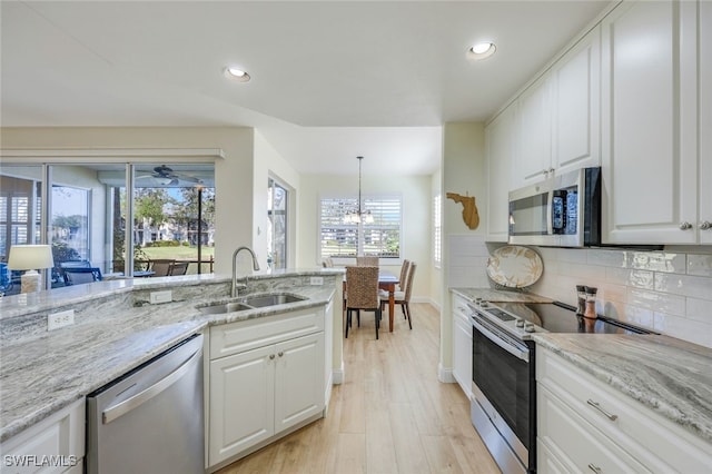 kitchen featuring stainless steel appliances, sink, white cabinets, tasteful backsplash, and pendant lighting