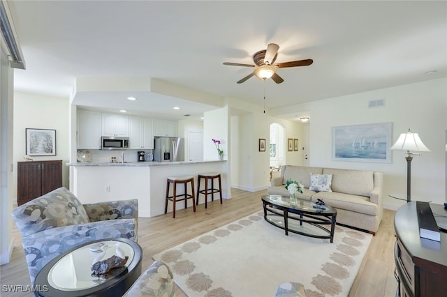 living room with ceiling fan and light hardwood / wood-style flooring