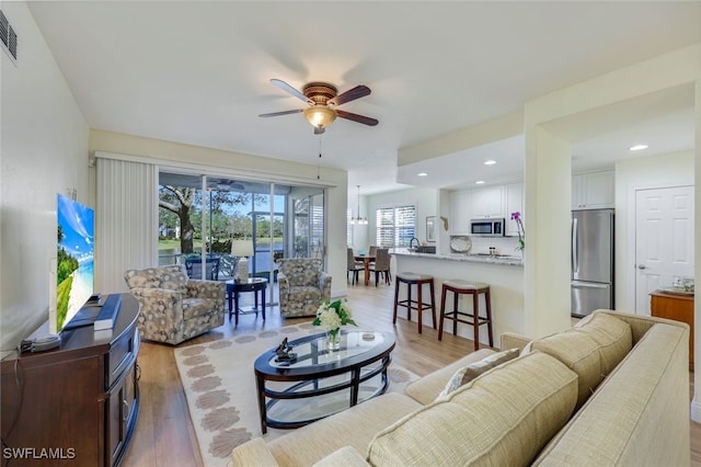 living area featuring a ceiling fan, recessed lighting, visible vents, and light wood-style flooring