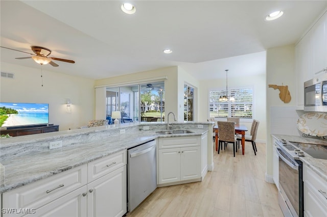 kitchen featuring appliances with stainless steel finishes, pendant lighting, sink, white cabinets, and ceiling fan with notable chandelier