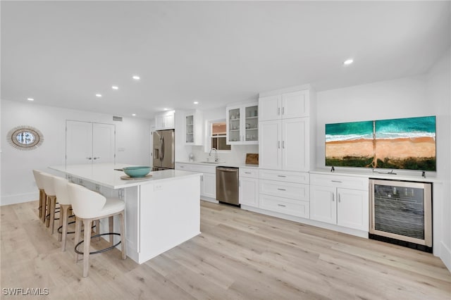 kitchen with white cabinets, beverage cooler, stainless steel appliances, and a kitchen island