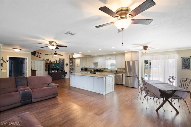 kitchen with a center island, crown molding, light stone counters, white cabinetry, and stainless steel appliances