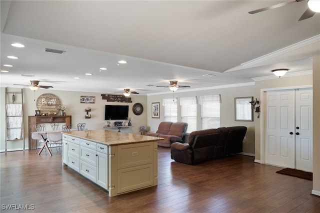 kitchen with a center island, white cabinets, dark hardwood / wood-style floors, light stone countertops, and ornamental molding