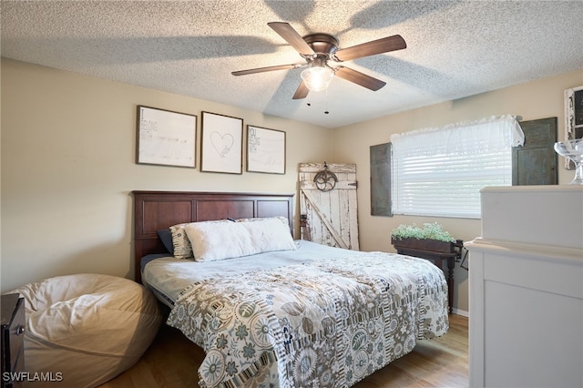 bedroom featuring a textured ceiling, light hardwood / wood-style flooring, and ceiling fan