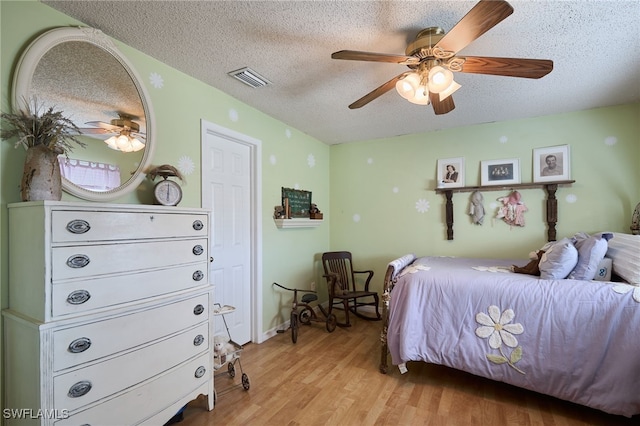 bedroom featuring ceiling fan, light wood-type flooring, and a textured ceiling