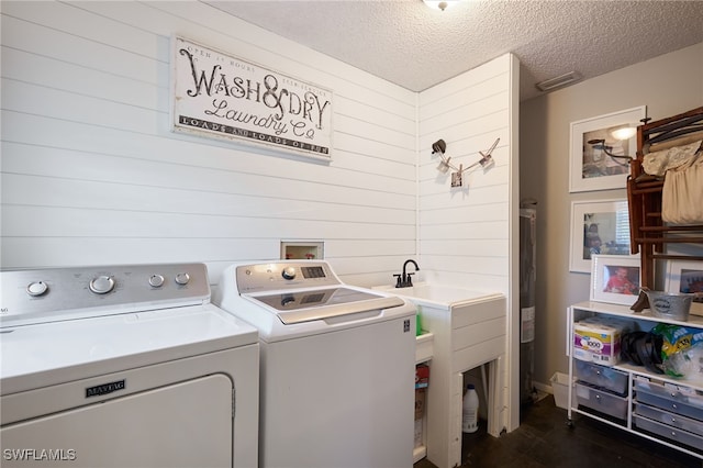 washroom with separate washer and dryer, wooden walls, and a textured ceiling