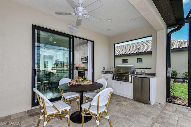 view of patio / terrace featuring area for grilling, ceiling fan, and exterior kitchen