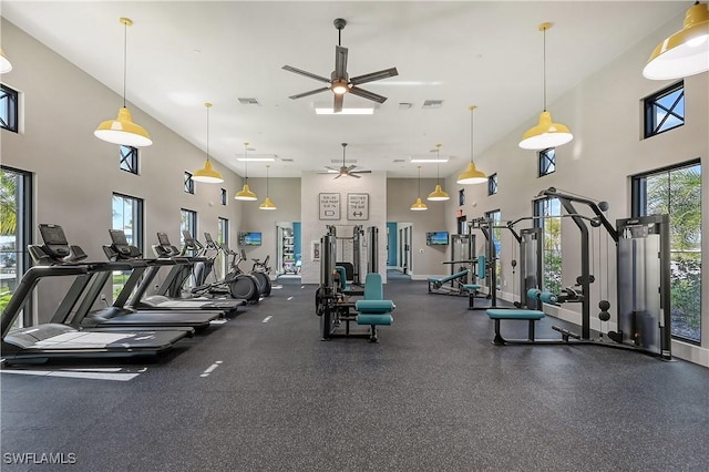 exercise room featuring ceiling fan and a towering ceiling