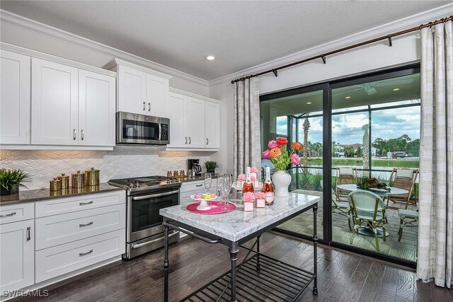 kitchen with white cabinetry, dark hardwood / wood-style flooring, crown molding, decorative backsplash, and appliances with stainless steel finishes