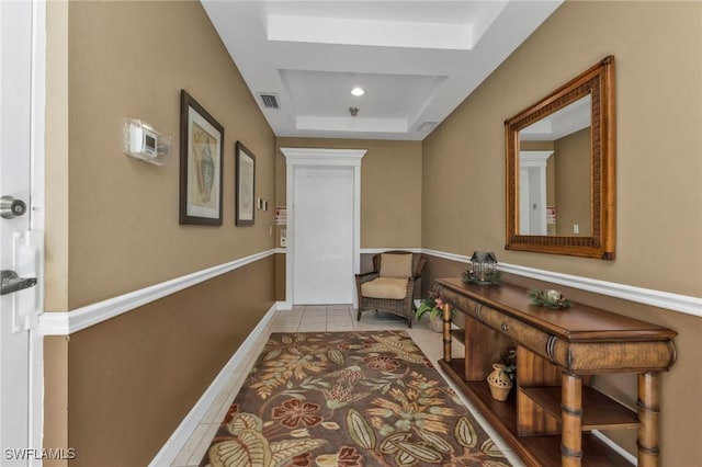 hall with a raised ceiling and light tile patterned floors