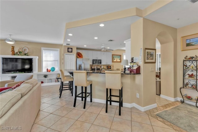 kitchen featuring a breakfast bar, white cabinets, ceiling fan, appliances with stainless steel finishes, and kitchen peninsula